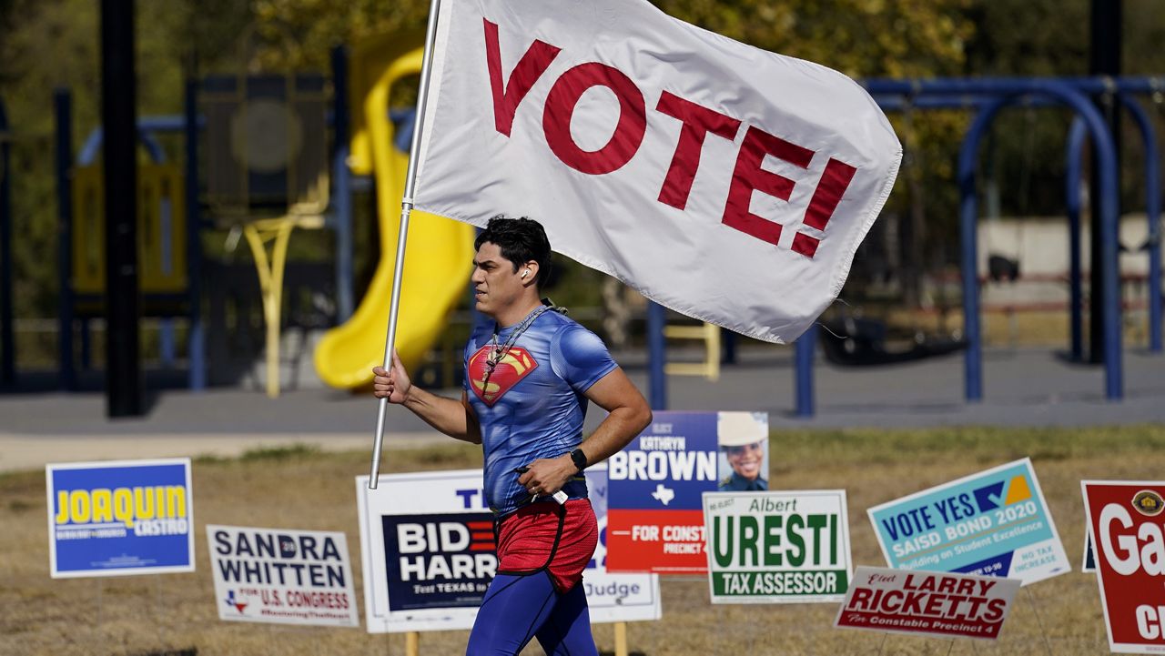 A jogger carries a Vote! flag as he passes a polling station, Tuesday, Nov. 3, 2020, in San Antonio. (AP Photo/Eric Gay)