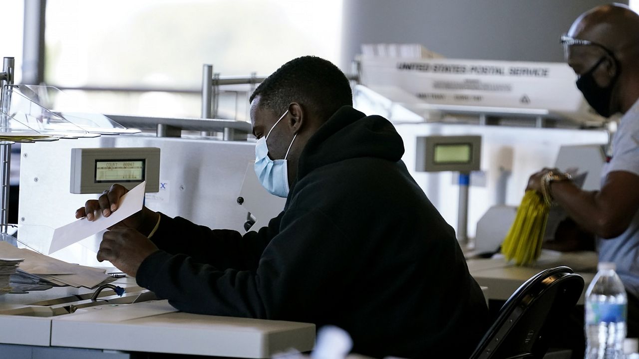 Election inspectors handle ballots as vote counting in the general election continues at State Farm Arena on Wednesday, Nov. 4, 2020, in Atlanta. (AP Photo/Brynn Anderson)