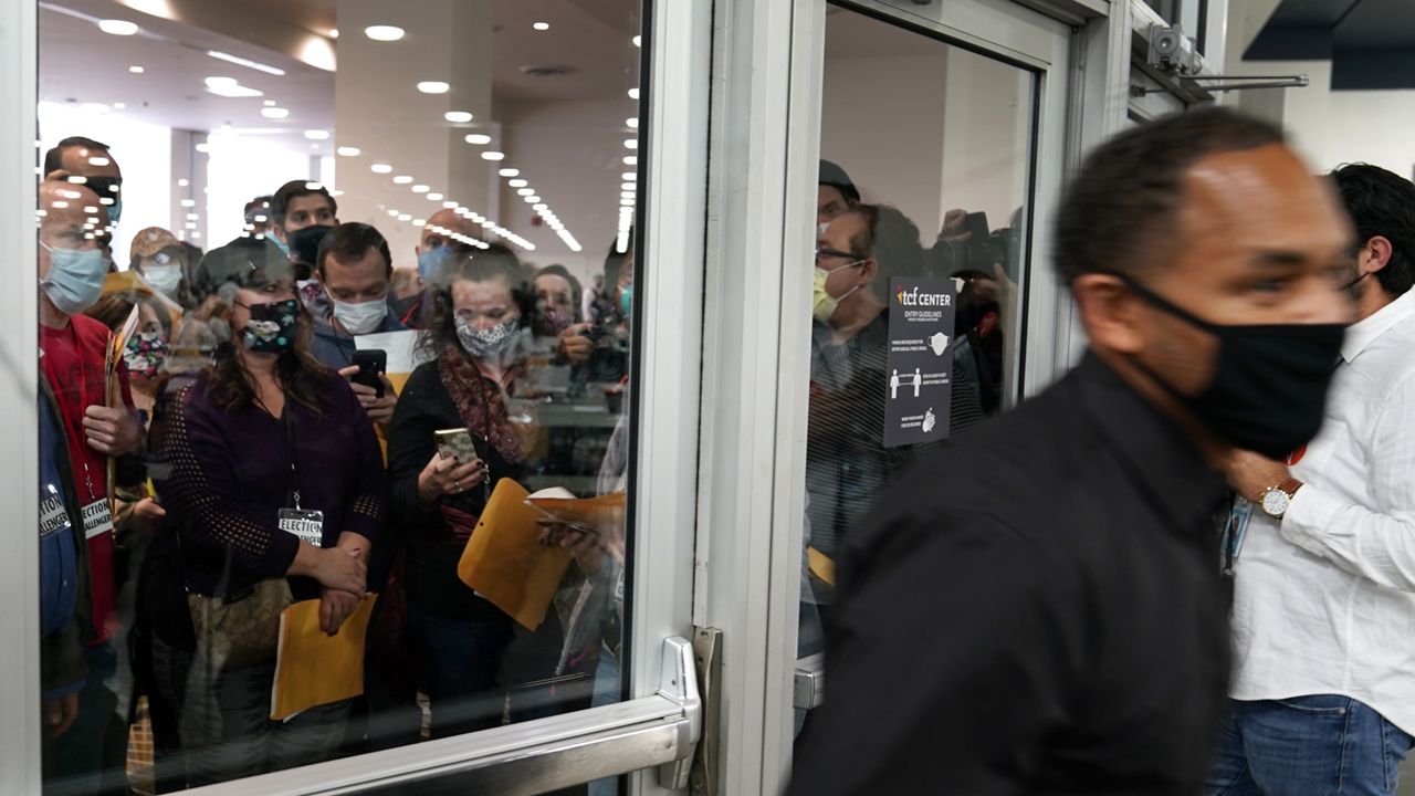 Election challengers, left, wait outside after an election official, right, closed the door to the central counting board, Wednesday, Nov. 4, 2020, in Detroit. Officials were saying the challenger quotas were met by Republicans, Democrats and Independent observers. (AP Photo/Carlos Osorio)