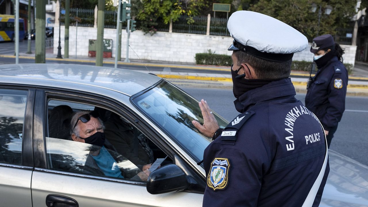 A policeman, wearing a face mask to protect against coronavirus, asks a passenger of a car to display his movement permission form, during lockdown in Athens on Nov. 7. (AP Photo/Yorgos Karahalis)