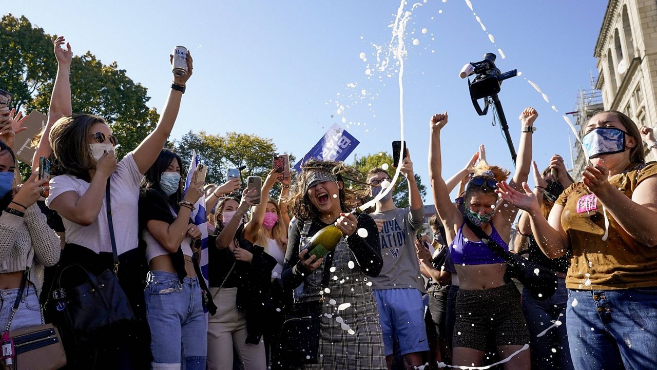 Amanda Madden sprays champagne as people celebrate Joe Biden's win at Black Lives Matter Plaza in Washington, D.C., on Saturday. (AP Photo/Alex Brandon)