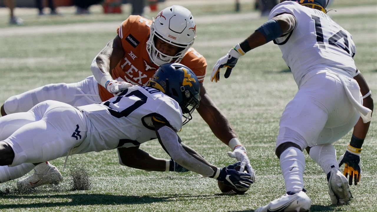 West Virginia's Alec Sinkfield (20) dives for a ball he fumbled against Texas' Roschon Johnson (2) in Austin, Texas, Saturday, Nov. 7, 2020. (AP Photo/Chuck Burton)