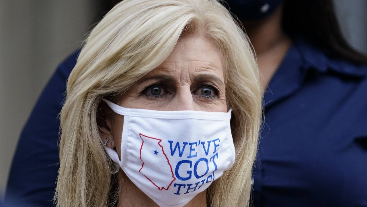 Fran Leathers, director and chair of the Oconee County Board of Elections wears a "We've Got This" mask as Georgia Secretary of State Brad Raffensperger speaks during a news conference on Wednesday in Atlanta. (AP Photo/Brynn Anderson)