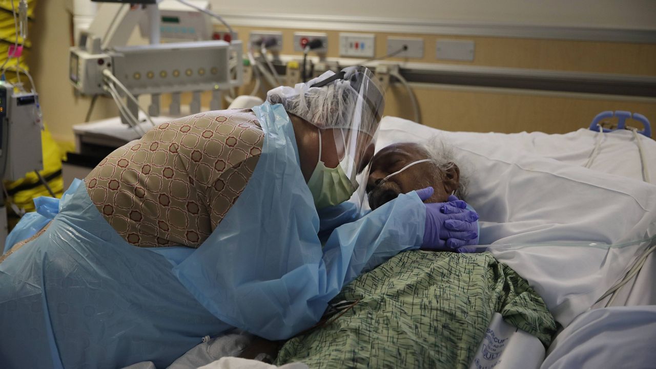 In this July 31, 2020, file photo, Romelia Navarro, 64, weeps while hugging her husband, Antonio, in his final moments in a COVID-19 unit at St. Jude Medical Center in Fullerton, Calif. (AP Photo/Jae C. Hong, File)