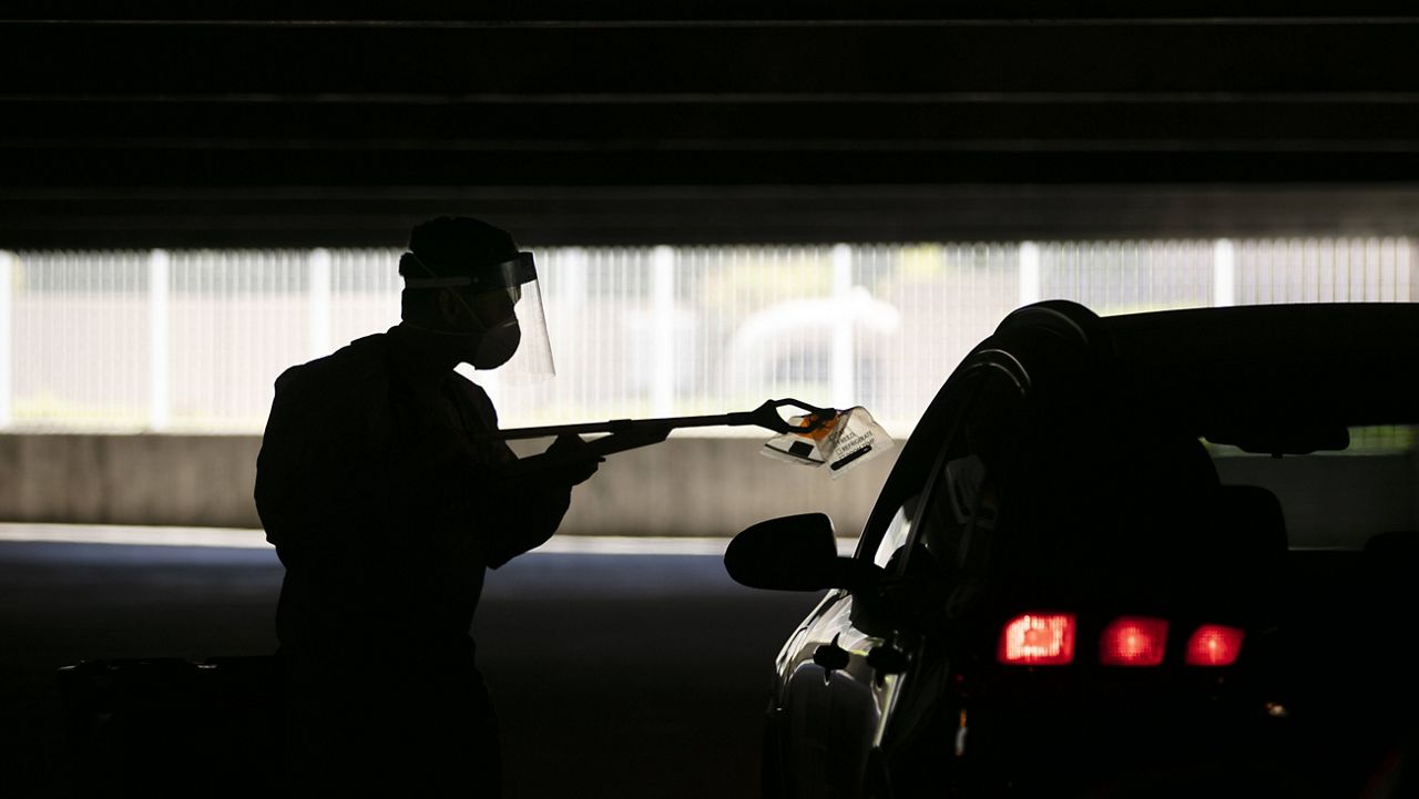 A physician assistant uses a grabber to collect a nasal swab sample at a COVID-19 drive-thru testing site set up at the Anaheim Convention Center in Anaheim, Calif. on July 16, 2020. (AP Photo/Jae C. Hong)