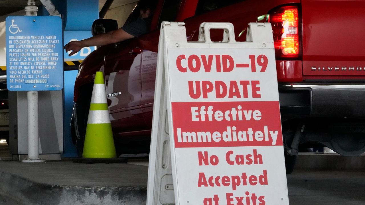 A sign posted reads "Covid-19 Update. Effective Inmediately. No Cash Accepted at Exits," at an LAX main parking lot. (AP Photo/Damian Dovarganes)