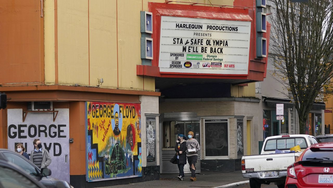 People wearing masks walk past the Harlequin Productions theatre in downtown Olympia, Wash., on Sunday. (AP Photo/Ted S. Warren)