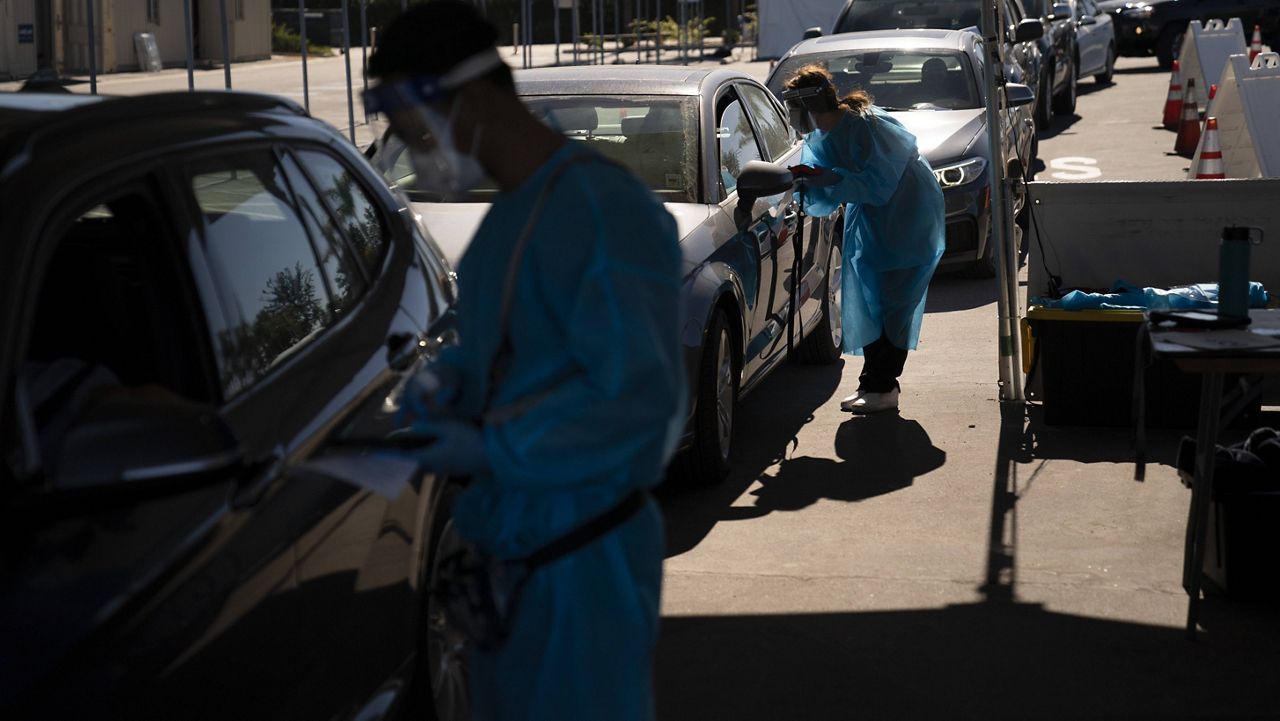 Medical assistants help people with COVID-19 testing at a testing site set up at the OC Fairgrounds in Costa Mesa, Calif., Monday, Nov. 16, 2020. (AP Photo/Jae C. Hong)