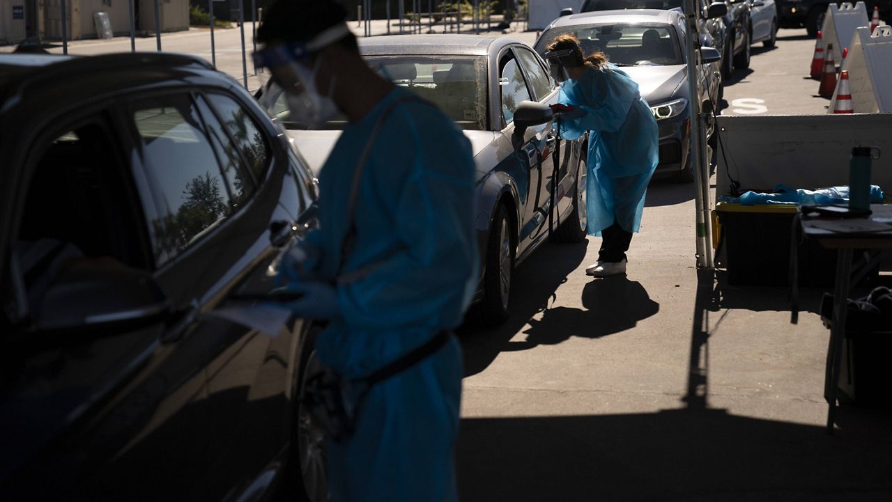 Medical assistants help people with COVID-19 testing at a testing site set up at the OC Fairgrounds in Costa Mesa, Calif., Monday, Nov. 16, 2020. (AP Photo/Jae C. Hong)