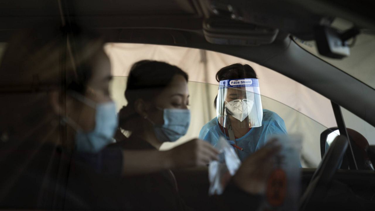 Medical assistant Linh Nguyen assists two women with COVID-19 testing at a testing site set up at the OC Fairgrounds in Costa Mesa, Calif., Nov. 16, 2020. (AP/Jae C. Hong)