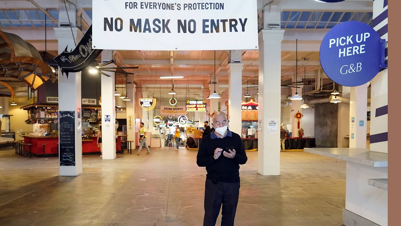 A sign points to a mask mandate at the Grand Central Market, Monday, Nov. 16, 2020, in Los Angeles. (AP Photo/Marcio Jose Sanchez)