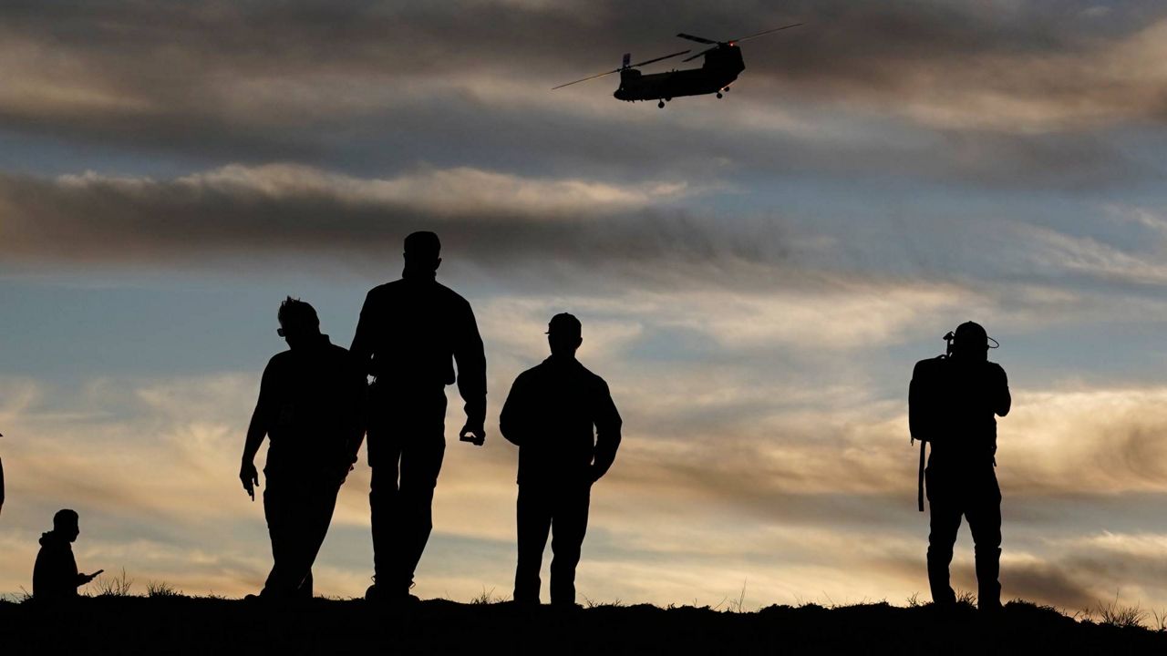 Firefighters watch a Chinook CH-47 helitanker take flight during a demonstration, Nov. 17, 2020, in the Santa Monica Mountains west of Los Angeles. (AP Photo/Marcio Jose Sanchez)