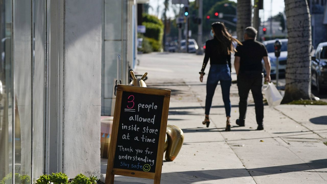 A sign restricting the number of customers stands outside of a shop Wednesday, Nov. 18, 2020, in West Hollywood, Calif. (AP Photo/Ashley Landis)