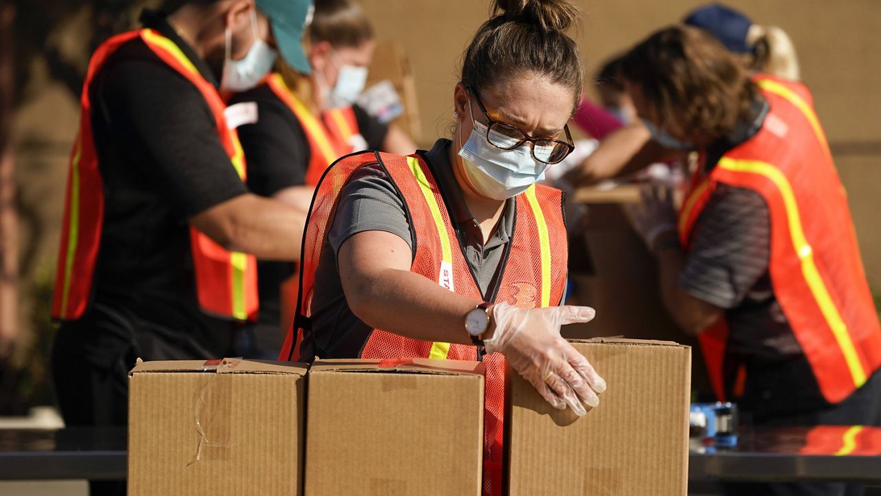 Kristen McKenna, center, and other volunteers pack boxes of food outside Second Harvest Food Bank in Thursday, Nov. 19, 2020, in Irvine, Calif. (AP Photo/Ashley Landis)