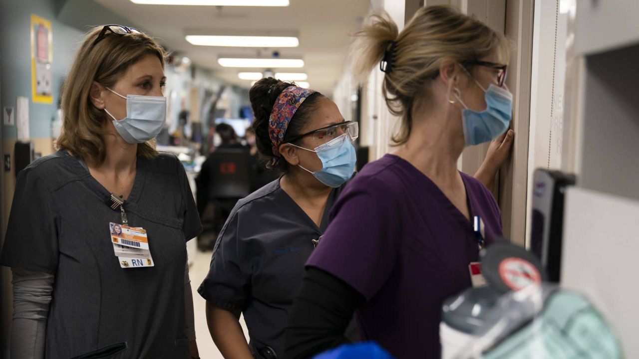 In this Nov. 19, 2020 file photo, a registered nurse, chaplain, and emergency room charge nurse watch as medical workers try to resuscitate a patient who tested positive for coronavirus at Providence Holy Cross Medical Center in L.A. (AP/Jae C. Hong)