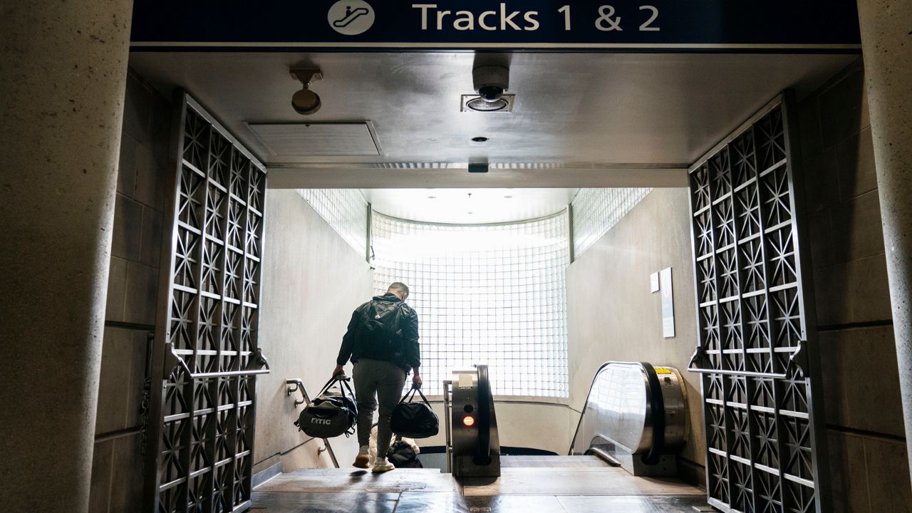 A passenger descends a staircase to board an Amtrak train, Friday, Nov. 20, 2020, in Providence, R.I.