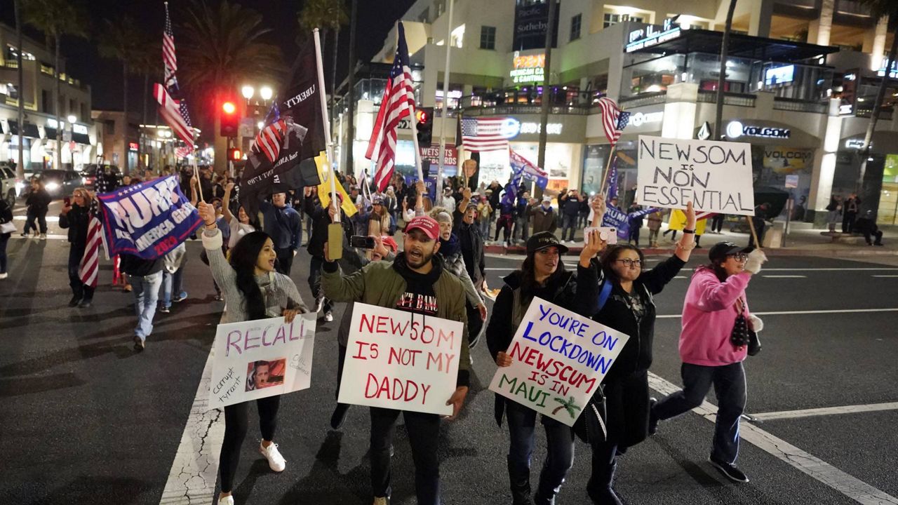 Demonstrators march across Pacific Coast Highway while shouting slogans Saturday, Nov. 21, 2020 during a protest against a stay-at-home order in Huntington Beach, Calif. (AP/Marcio Jose Sanchez)
