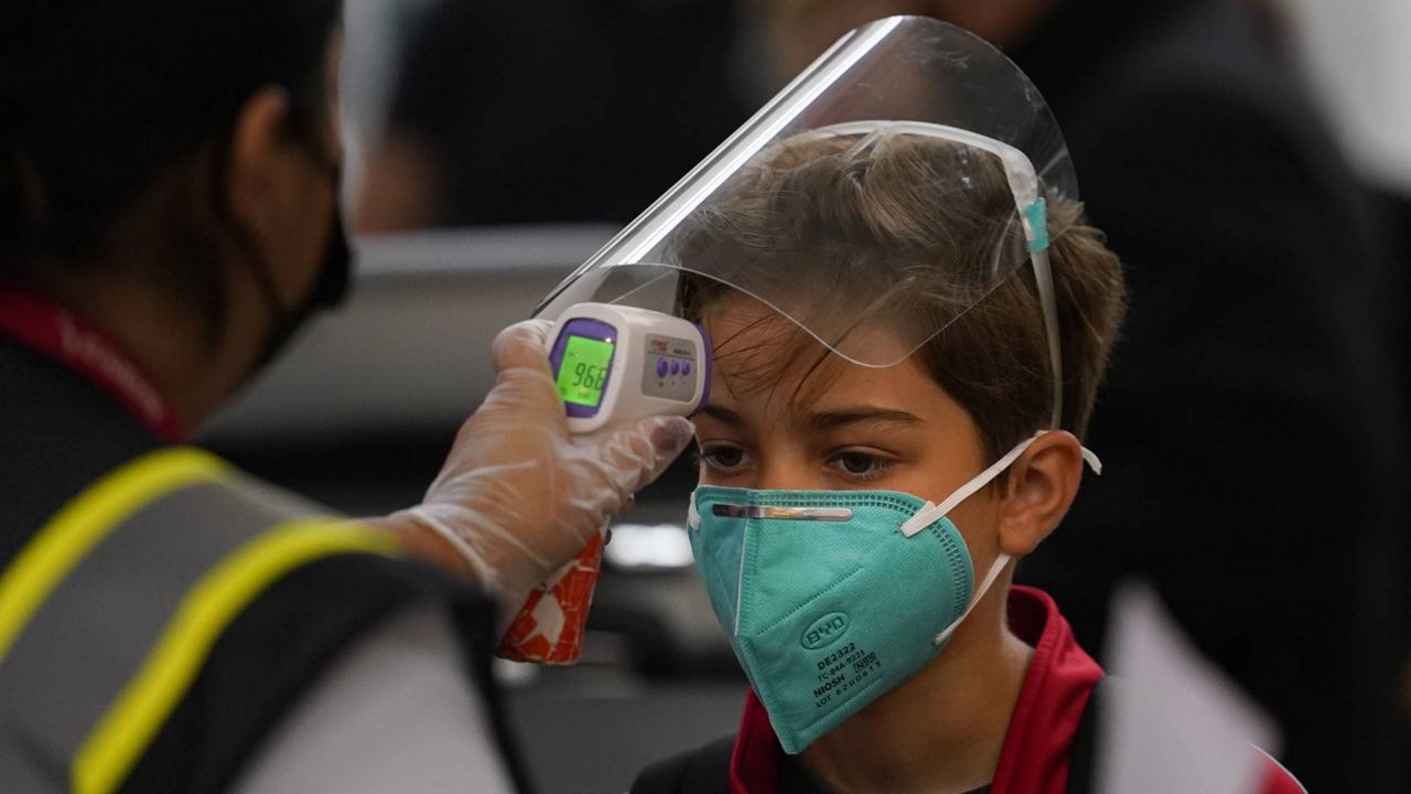 A boy gets his temperature checked while waiting in line to check in at the Los Angeles International Airport, Monday, Nov. 23, 2020. (AP/Jae C. Hong)