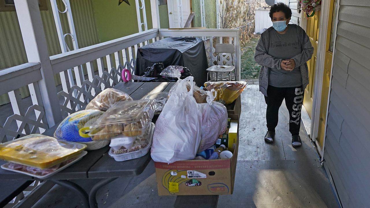 Evelyn Maysonet looks at the food delivery from the Weber-Morgan Health Department Tuesday, Nov. 24, 2020, in Ogden, Utah. (AP Photo/Rick Bowmer)