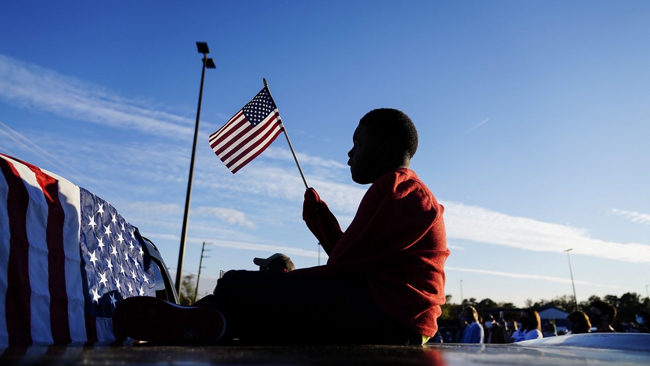FILE - In this Nov. 15, 2020, file photo Xavier Watts, 9, waves an American flag during a camping rally for Georgia Democratic U.S. Senate candidates Jon Ossoff and Raphael Warnock in Marietta, Ga. (AP Photo/Brynn Anderson, File)
