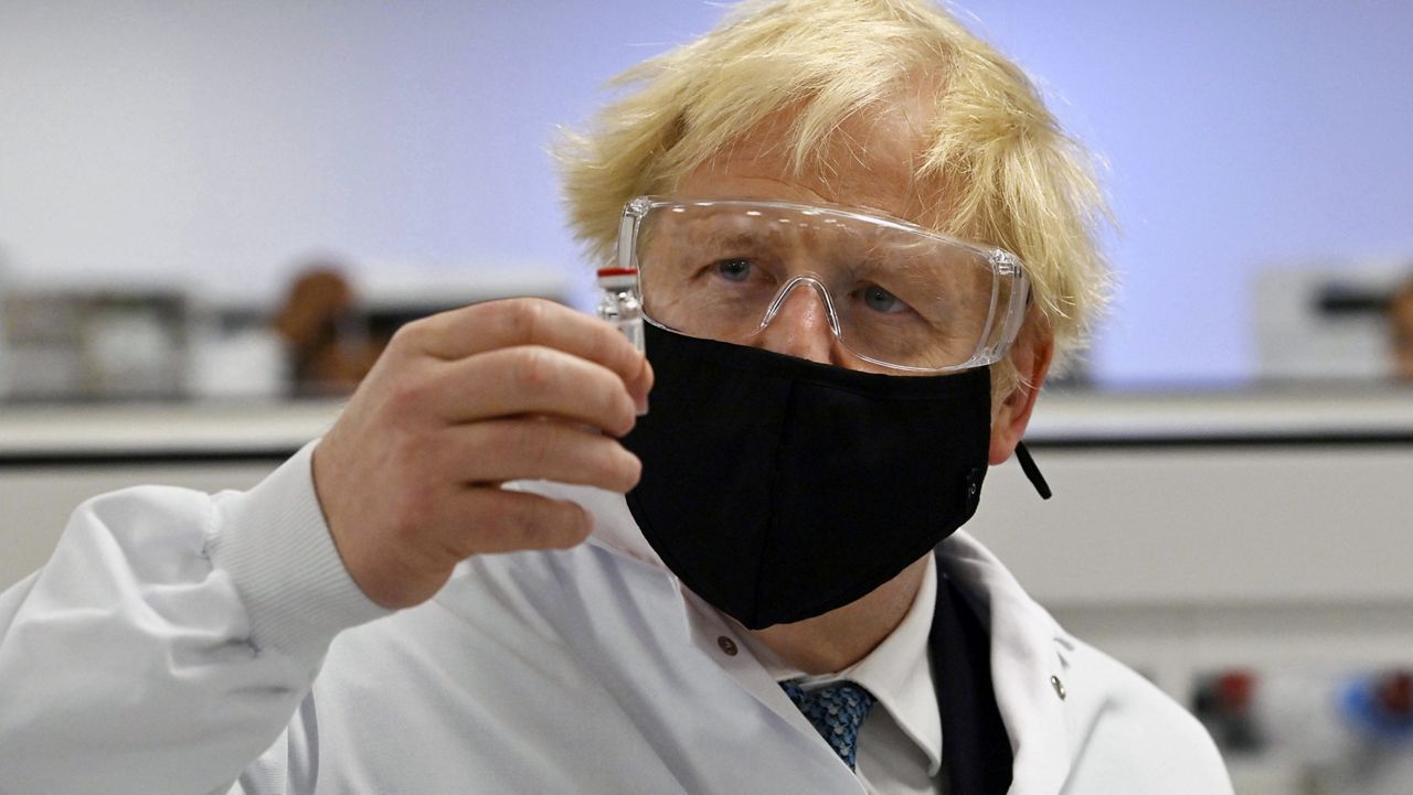 Britain's Prime Minister Boris Johnson holds a vial of the Oxford/AstraZeneca vaccine Covid-19 candidate vaccine, known as AZD1222, at Wockhardt's pharmaceutical manufacturing facility in Wrexham, Wales, Monday, Nov. 30, 2020. (Paul Ellis/PA via AP)