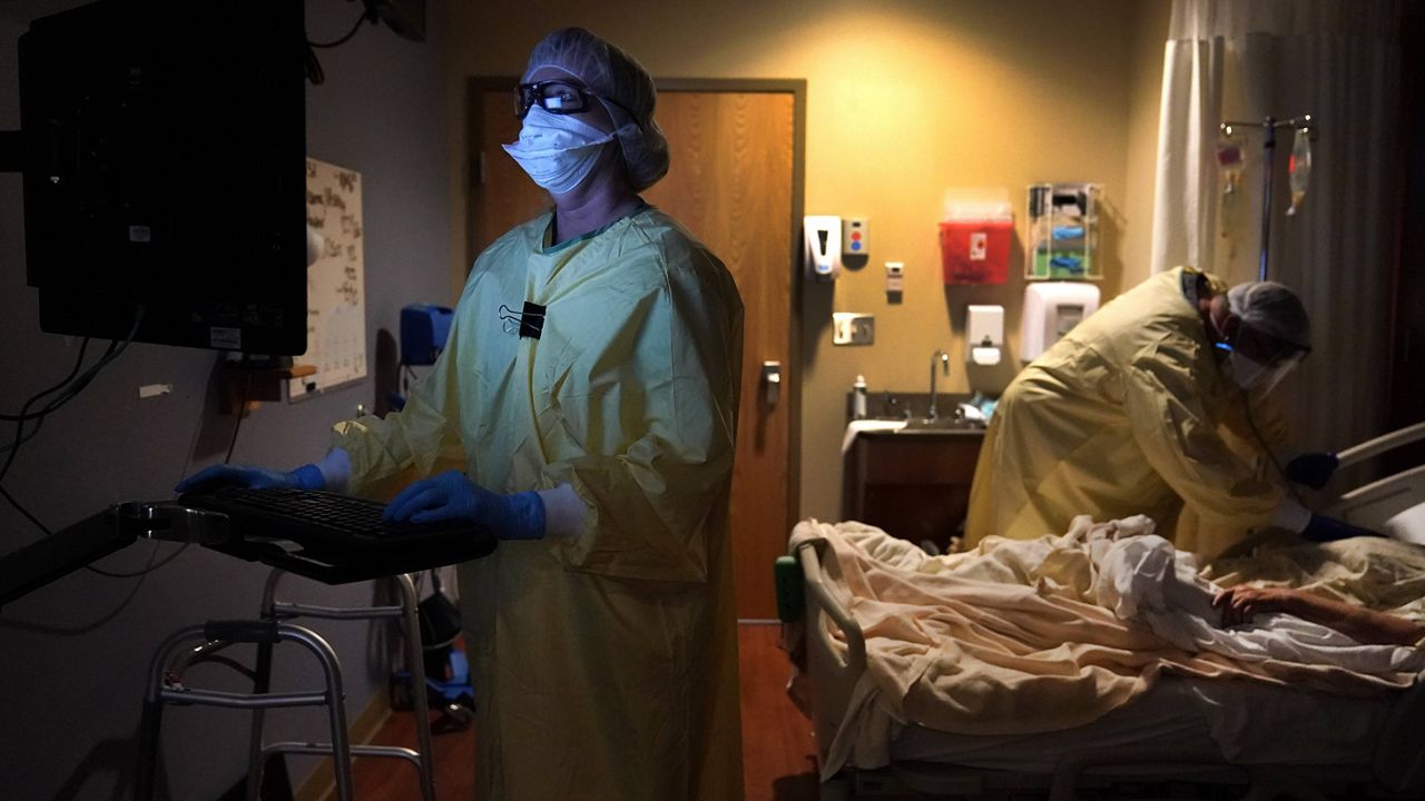 A nurse in Memphis, Mo., is illuminated by the glow of a computer monitor as a doctor examines a COVID-19 patient on Nov. 24. (AP Photo/Jeff Roberson)