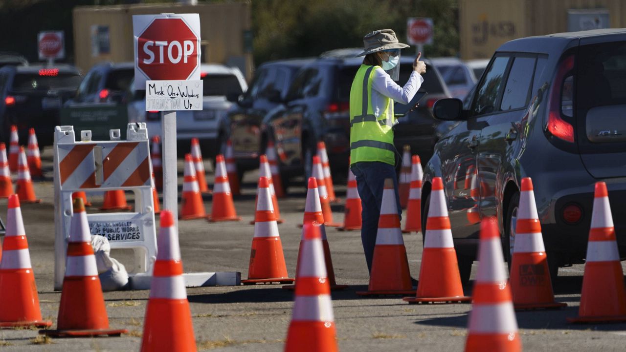 Drivers with appointments wait in line to get a free COVID-19 self-test at Dodger Stadium in Los Angeles, Tuesday, Dec. 1, 2020. (AP Photo/Damian Dovarganes)
