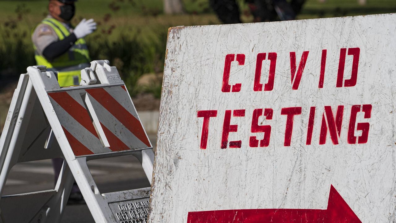 A COVID testing sign directs drivers waiting in line to get a free COVID-19 self-test at Dodger Stadium in Los Angeles, Tuesday, Dec. 1, 2020. (AP Photo/Damian Dovarganes)
