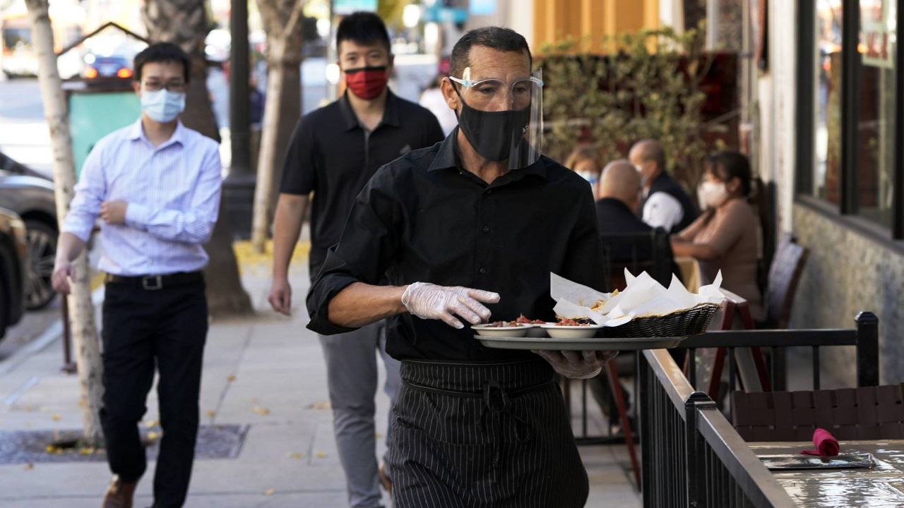 A waiter wears a mask and face covering at a restaurant with outdoor seating Tuesday, Dec. 1, 2020, in Pasadena, Calif. (AP/Marcio Jose Sanchez)
