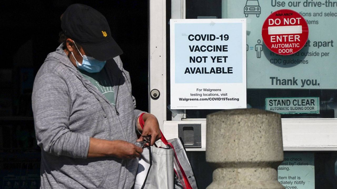 A customer walks past a sign indicating that a COVID-19 vaccine is not yet available at Walgreens, Dec. 2, 2020, in Long Beach, Calif. (AP Photo/Ashley Landis)