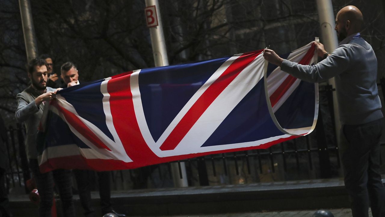 FILE - In this Friday, Jan. 31, 2020 file photo, the Union flag is folded and removed after being lowered from outside of the European Parliament in Brussels. (AP Photo/Francisco Seco, File)