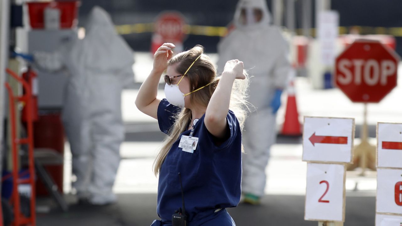 FILE PHOTO: In this Friday, March 13, 2020 file photo, Medical University of South Carolina project manager Amy Jackson adjusts her face mask as healthcare providers dress in protective suiting, in Charleston, S.C. (AP Photo/Mic Smith, File)