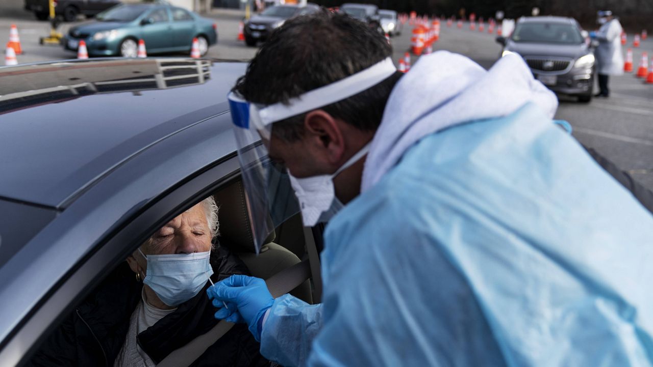 Beverly Palazzi is swabbed for COVID-19 by Milton Giard at a testing site set up outside McCoy Stadium in Pawtucket, R.I., on Wednesday, Dec. 9. (AP Photo/David Goldman)