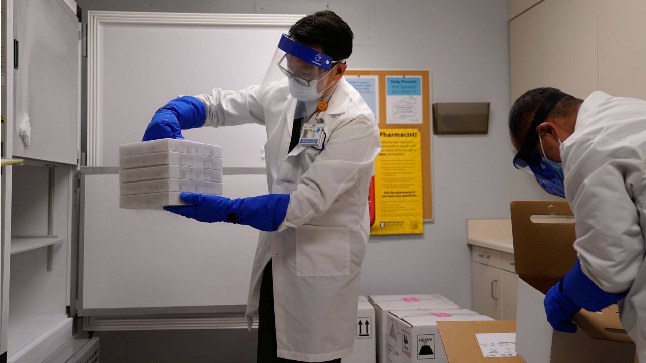 Director of inpatient pharmacy David Cheng, center, places trays of the Pfizer-BioNTech COVID-19 vaccine into a freezer at Kaiser Permanente Los Angeles Medical Center, Dec. 14, 2020. (AP Photo/Jae C. Hong)
