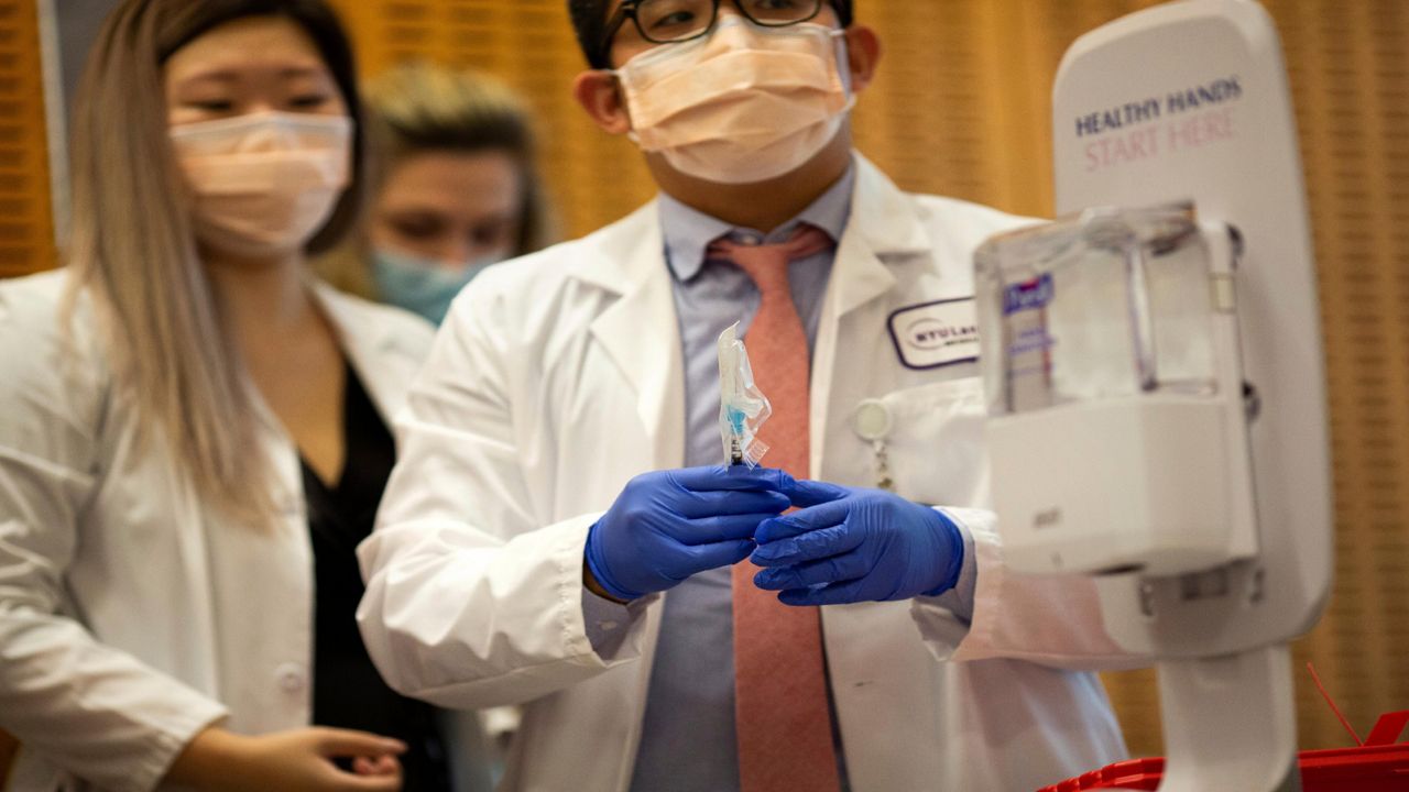 A pharmacist holds a syringe containing the first dose of the COVID-19 vaccine to be administered at NYU-Langone Hospital on Monday, Dec. 14, 2020, in New York.