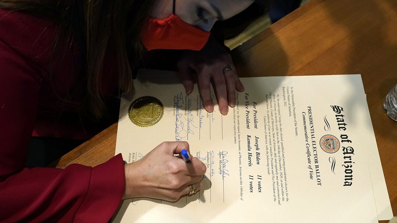 Tucson Mayor Regina Romero, a member of Arizona's Electoral College, signs a commemorative copy of the Arizona Presidential Electoral Ballot after casting a vote in the Arizona Electoral College Monday, Dec. 14, 2020, in Phoenix. (AP Photo/Ross D. Franklin, POOL)