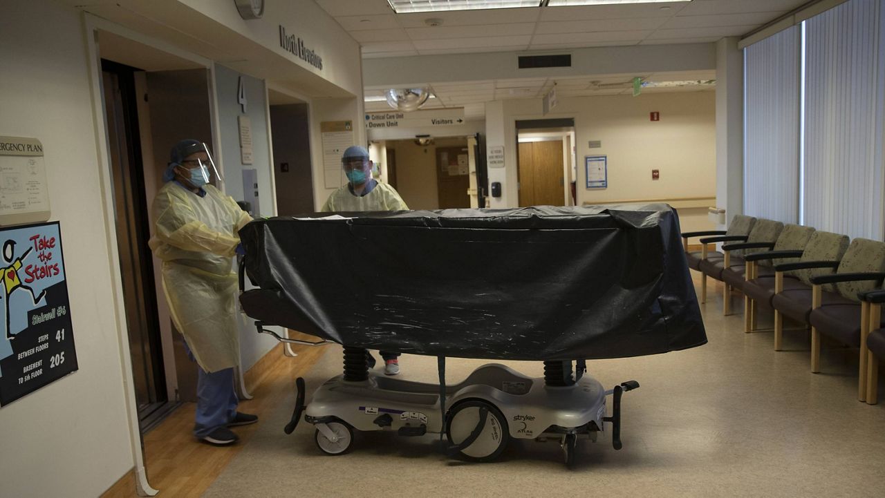In this July 7, 2020, file photo, hospital staff members enter an elevator with the body of a COVID-19 victim on a gurney at St. Jude Medical Center in Fullerton, Calif. (AP Photo/Jae C. Hong, File)