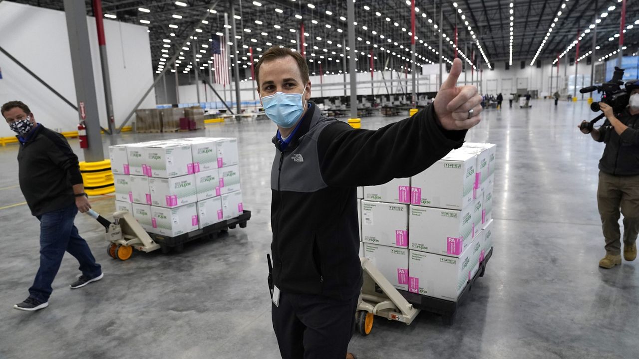 A worker gives a thumbs up while transporting boxes containing the Moderna COVID-19 vaccine to the loading dock for shipping at the McKesson distribution center in Olive Branch, Miss., Sunday, Dec. 20, 2020. (AP Photo/Paul Sancya, Pool)