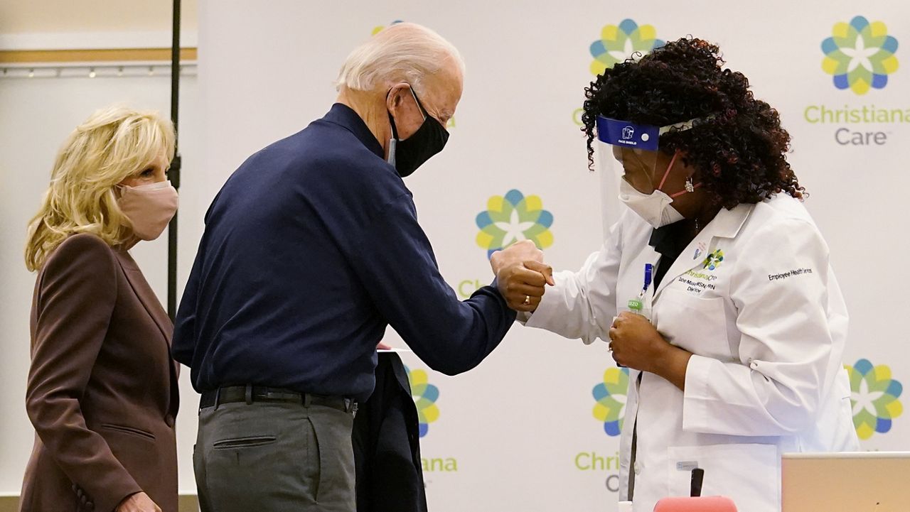 President-elect Joe Biden fist bumps with nurse practitioner Tabe Mase after receiving his first dose of the coronavirus vaccine at ChristianaCare Christiana Hospital in Newark, Del., Monday, Dec. 21, 2020, as Dr. Jill Biden looks on. (AP Photo/Carolyn Kaster)
