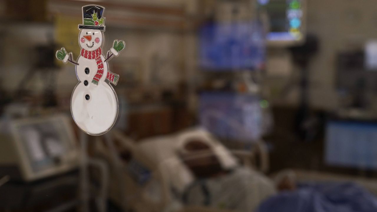 A glass wall is decorated with a snowman as a COVID-19 patient lies in a bed in an intensive care unit at Providence Holy Cross Medical Center in the Mission Hills section of Los Angeles, Tuesday, Dec. 22, 2020. (AP Photo/Jae C. Hong)