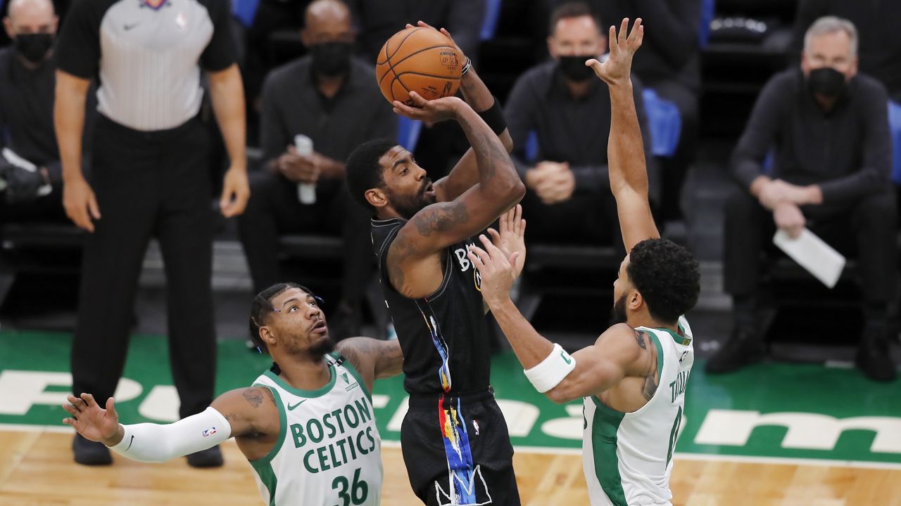 Brooklyn Nets' Kyrie Irving shoots against Boston Celtics' Marcus Smart (36) and Jayson Tatum (0) during the first half of an NBA basketball game, Friday, Dec. 25, 2020, in Boston. (AP Photo/Michael Dwyer)