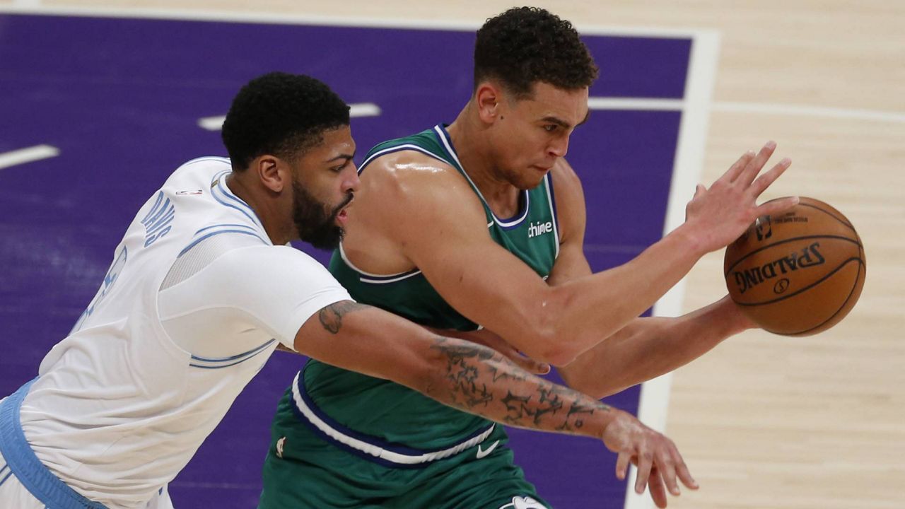 Anthony Davis, left, tries to knock the ball away from Dallas Mavericks' Dwight Powell during an NBA game Dec. 25, 2020, in Los Angeles. (AP/Ringo H.W. Chiu)