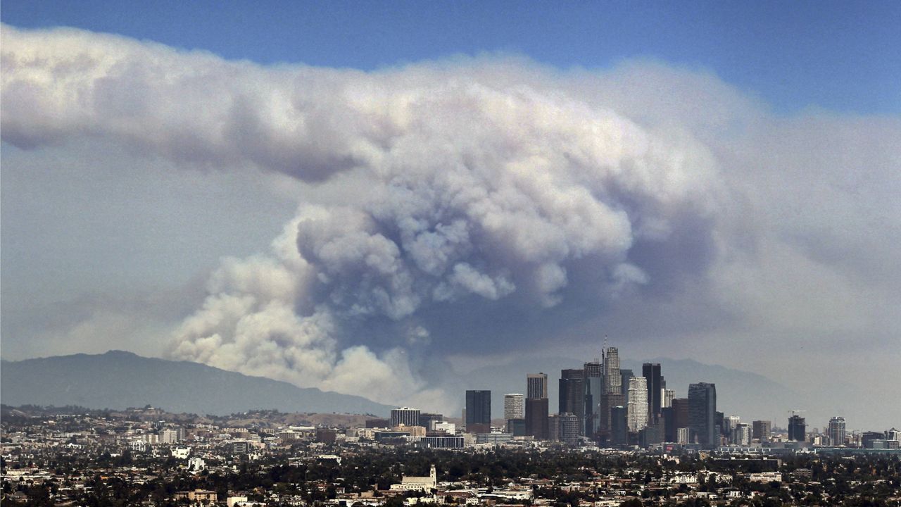 In this Monday, June 20, 2016 file photo, smoke from wildfires burning in Angeles National Forest fills the sky behind the Los Angeles skyline. (AP Photo/Ringo H.W. Chiu)
