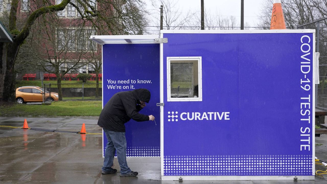 A person holds a swab, Saturday, Jan. 2, 2021, at a walk-up kiosk testing site for COVID-19 at the Garfield Community Center in Seattle. (AP Photo/Ted S. Warren)