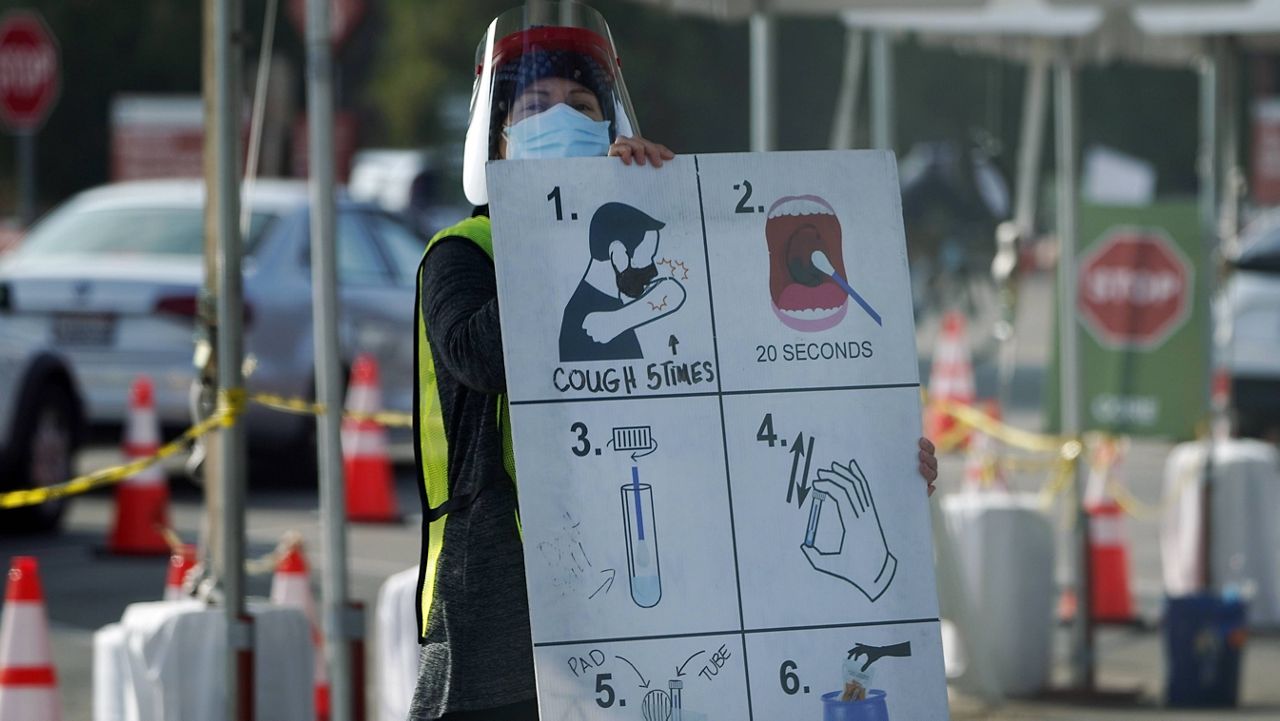 A worker gives instructions to motorists at a COVID-19 testing site Tuesday, Jan. 5, 2021, in Los Angeles. (AP Photo/Marcio Jose Sanchez)