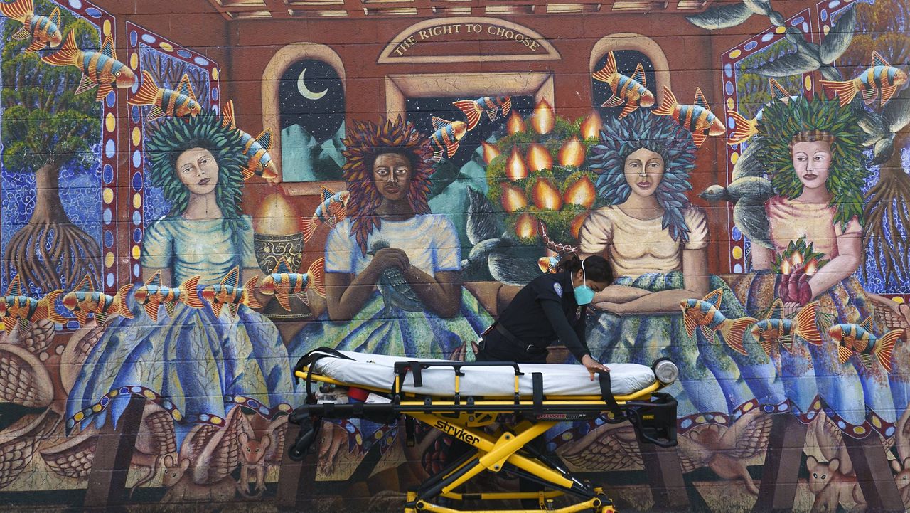 Ana Galicia readies a stretcher after transporting a patient, outside Exodus Mental Health Urgent Care Clinic in Los Angeles on Tuesday, Jan. 5, 2021. (AP Photo/Damian Dovarganes)