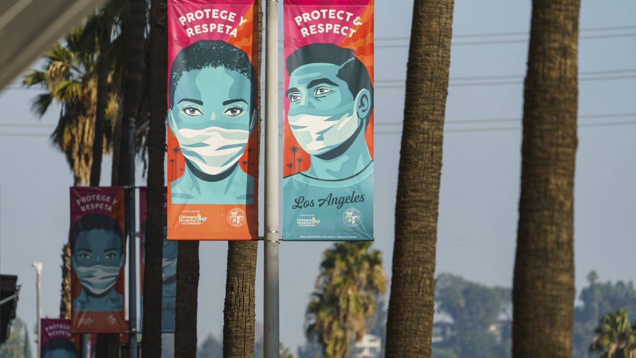 Banners advising people to wear masks against the coronavirus hang along Hollywood Boulevard in Los Angeles on Tuesday, Jan. 5, 2021. (AP Photo/Damian Dovarganes)