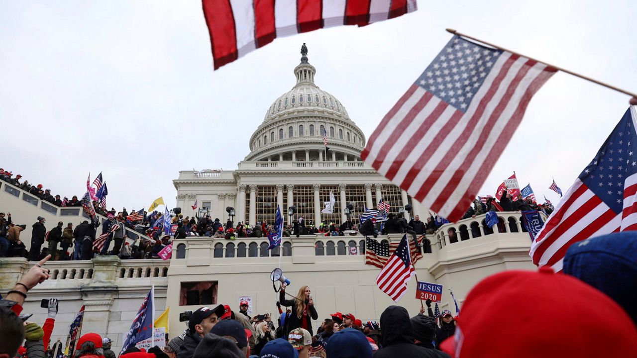 Supporters of President Donald Trump waving flags and a "Jesus 2020" sign gather outside the U.S. Capitol in Washington on Jan. 6, 2021. (AP Photo/Shafkat Anowar)