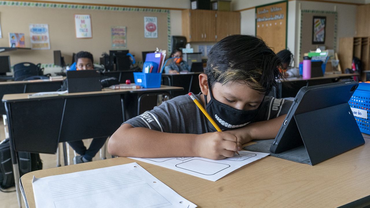 FILE - This file photo from Thursday, Oct. 1, 2020, shows a student wearing a face mask while doing work at his desk at the Post Road Elementary School in White Plains, N.Y. (AP Photo/Mary Altaffer, File)