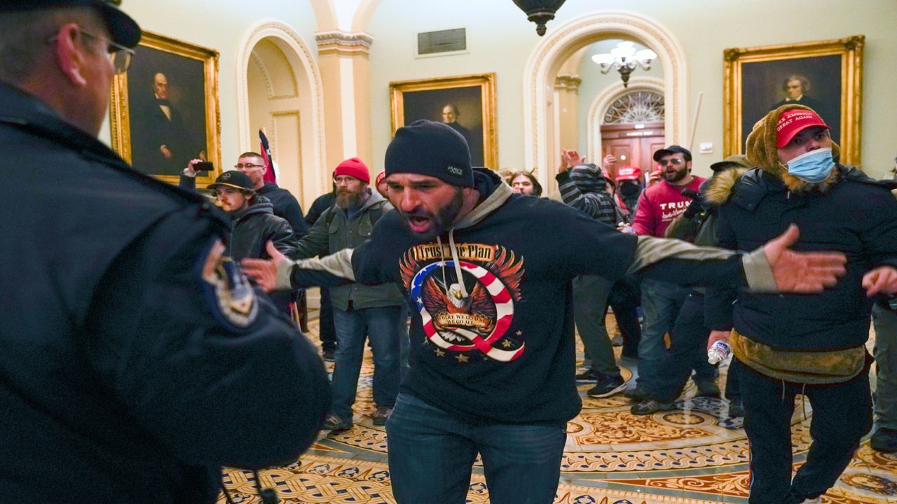 Trump supporters gesture to U.S. Capitol Police in the hallway outside of the Senate chamber at the Capitol in Washington. The U.S. registered its highest deaths yet from the coronavirus on the same day as a mob attack on the nation’s capitol laid bare some of the same, deep political divisions that have hampered the battle against the pandemic.